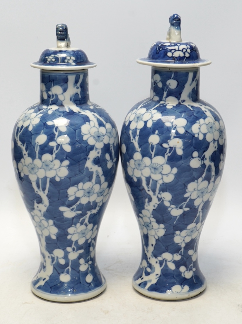 A pair of Chinese blue and white prunus baluster vases and covers, 31cm high. Condition - one vase good, the other pieces poor